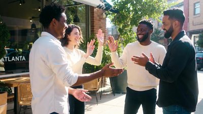 Four new friends greeting each other outside an Atlanta cafe